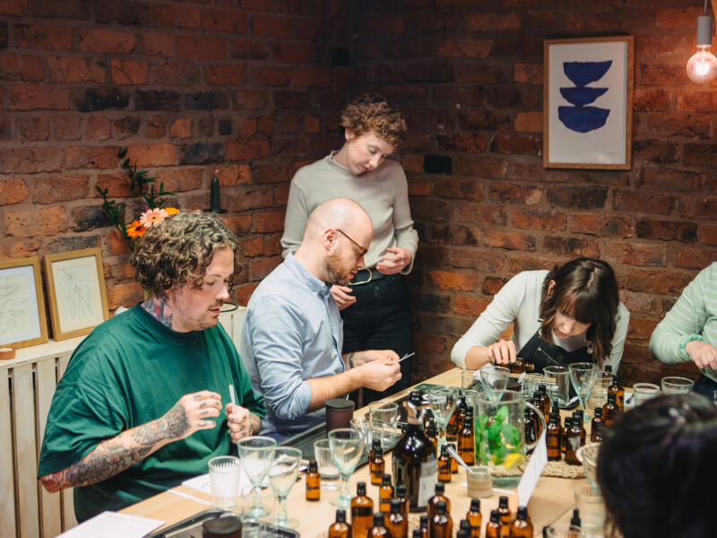 People measure and smell oils in a beauty Manchester class.